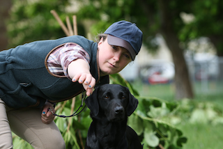 lady with a black Labrador, she is pointing something out to the Labrador which is off camera 